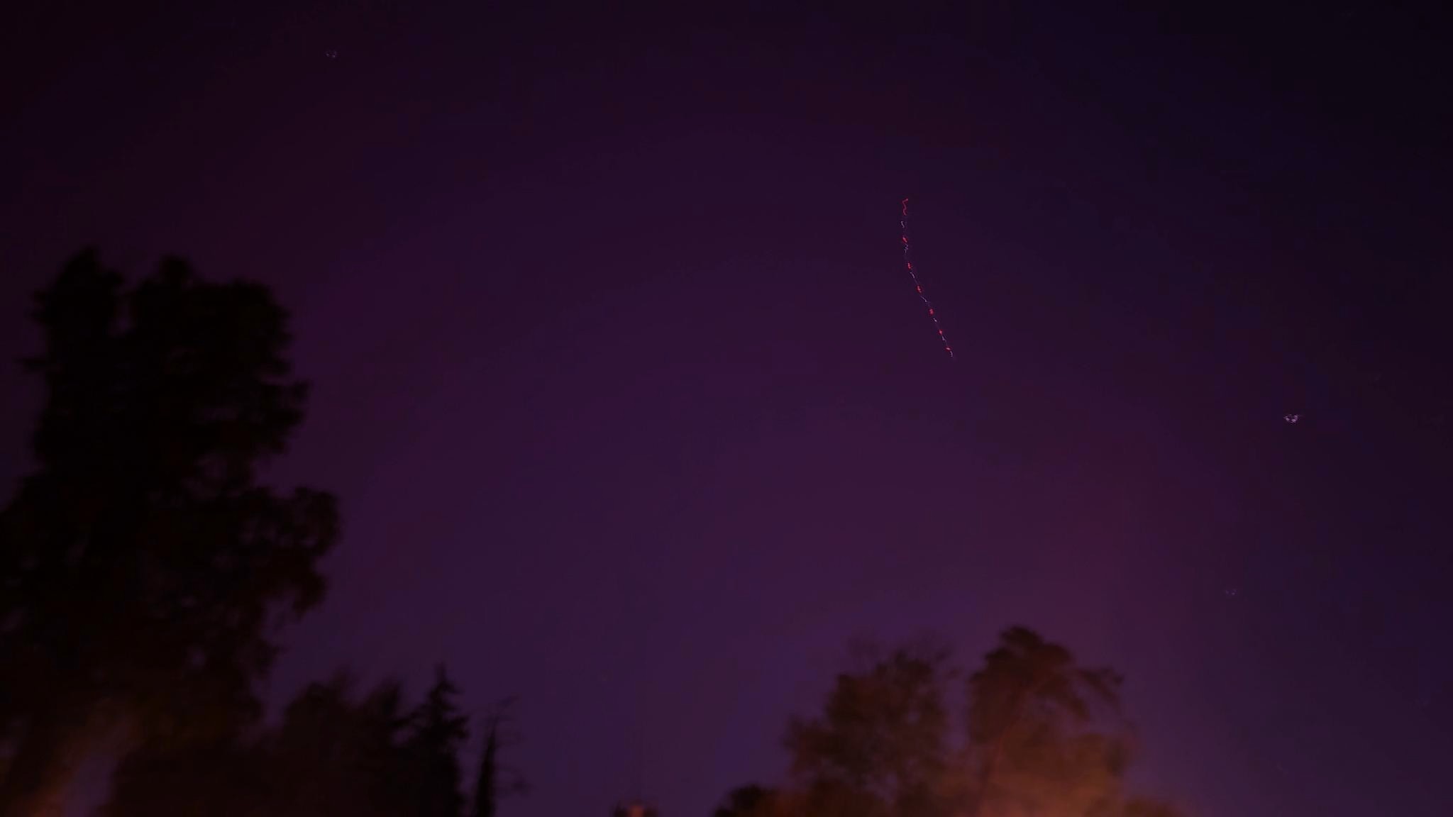 Blurry long exposure of the October 2024 pink-purple aurora above Belmont Plateau, Philadelphia, including the path of a satellite in the sky. Photo by me.